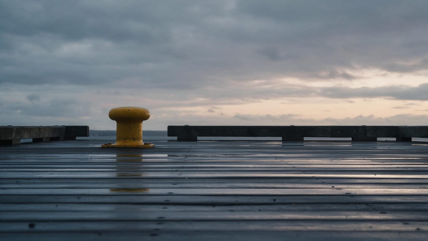 Pier at dusk with one yellow bollard